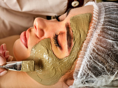 泥面部面膜的 spa 沙龙的女人。脸上的程序