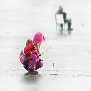 小孩子在冬天结冰的湖面上钓鱼