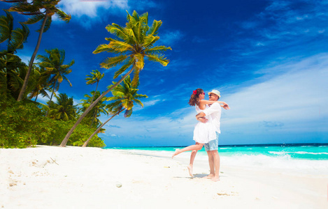 快乐的年轻夫妇，在白色的衣服在海边玩