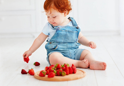 可爱姜蹒跚学步婴儿品尝草莓