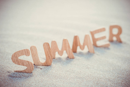 夏天。在沙滩上的木制字母