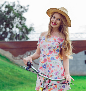 美丽的金发女孩骑自行车在公园里的肖像