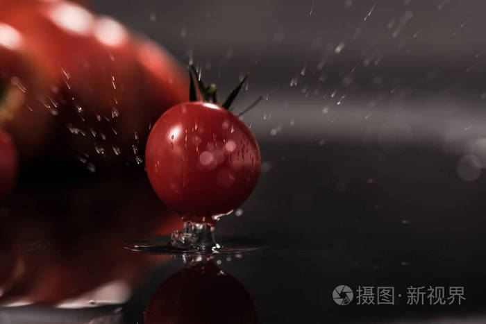 在黑色背景上的西红柿,水滴镜子