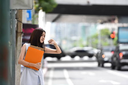 亚洲业务女子等候在一个城市一辆出租车