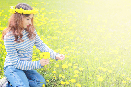 在一个晴朗的日子，在草地上的黄色的蒲公英上休息的女孩