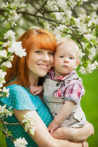 快乐幸福的母亲和儿子在春天的花园里的肖像
