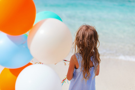 小女孩与气球在海滩后面观