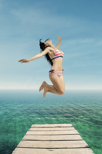 激动的女人，在泳衣跳在码头