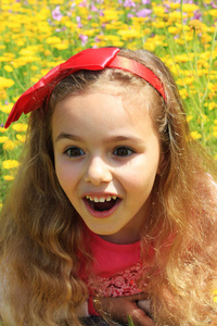 微笑小漂亮的女孩，在黄色的花。上的红色蝴蝶结结
