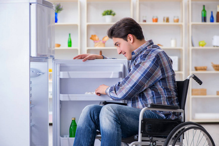 年轻的残疾受伤的男子打开冰箱门