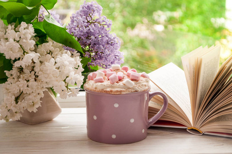 有棉花糖，打开书和鲜花花束在窗台上的咖啡杯。概念家早餐和阅读。夏天还是春天的季节