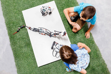 两个年轻男孩在玩机器人，教育和玩概念