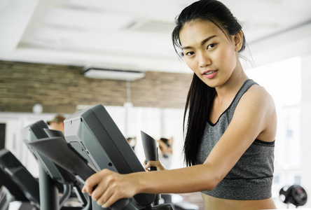 在椭圆机在健身房锻炼的亚洲女人
