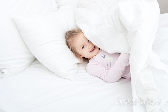 孩子在柔软的床上的小女孩