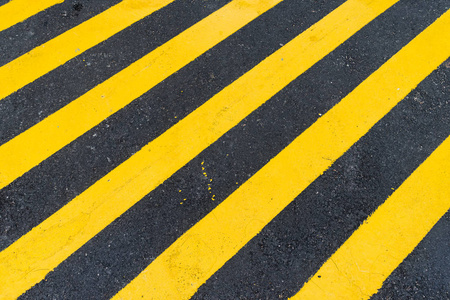 沥青与对角线的黑色和黄色警告条纹背景