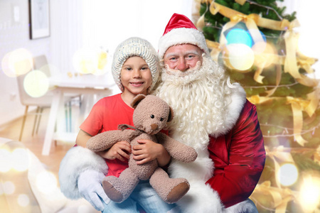 真正的圣诞老人与小男孩和泰迪熊在家里。圣诞节和新年庆典