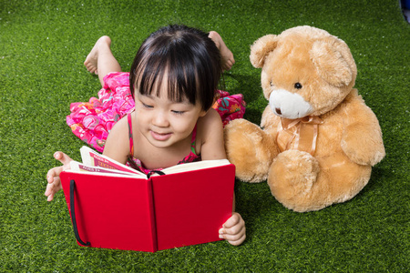 亚洲中国小女孩读书与泰迪熊