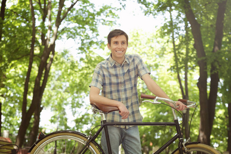 年轻英俊的男子，脚踏车在户外的阳光灿烂的日子