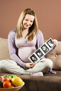 怀孕的女人拿着超声张照片