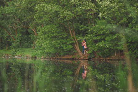 情人湖。年轻夫妇的爱情坐在公园地面附近的水而这些年轻的男子，在日落的时候弹吉他