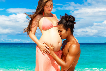 热带的海滩上开心快乐年轻的怀孕夫妇