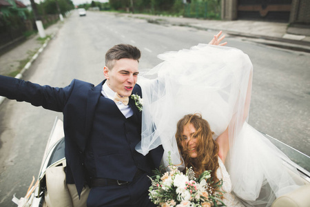 时尚的婚礼夫妇，新娘，新郎亲吻和拥抱上复古车