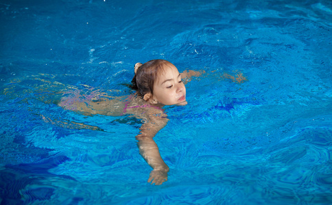 试图抓住水表面在游泳池里的女孩