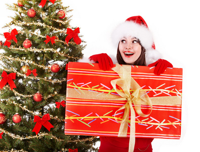 在圣诞老人的帽子和杉木树中与红色礼品盒圣诞女孩