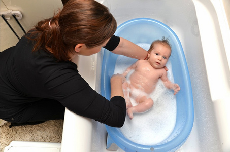初生婴儿浴在蓝色浴缸由母亲