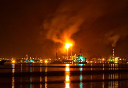 在晚上与污染了大气层的巨大烟雾列炼油厂