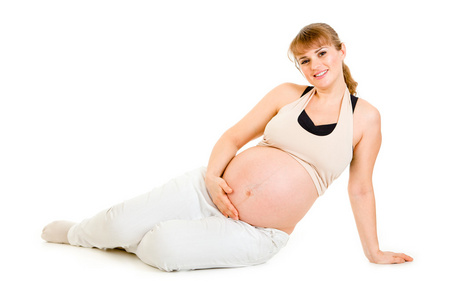 快乐美丽的孕妇坐在地板上和着她的肚子里