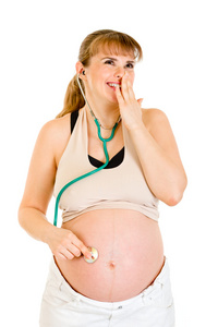 惊奇怀孕的女人在她的肚子上拿听诊器