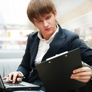 英俊的年轻男子在咖啡馆，bu 工作用的笔记本电脑的肖像