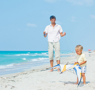 男孩与父亲玩风筝的海滩上