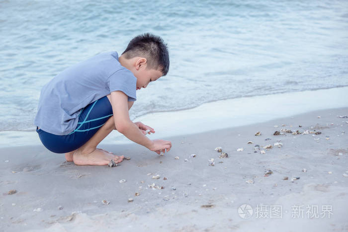 在海滩上捡贝壳的男孩
