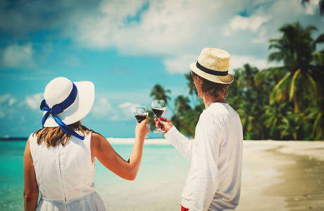 幸福恩爱的夫妻在海滩喝葡萄酒