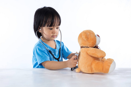 亚洲中国小姑娘医生检查玩具熊