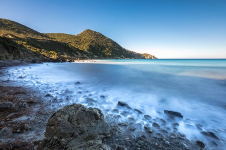 慢速快门的海浪拍打岩石在科西嘉岛上的照片