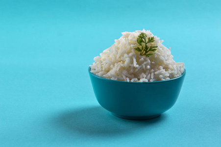煮熟的纯白色印度香米与香菜在蓝色背景上的蓝色碗米饭