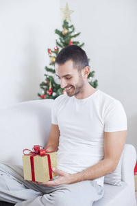 男人在沙发上抱着一份圣诞礼物