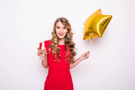 年轻女人穿着红色与金色的星星形气球微笑和在白色背景喝香槟