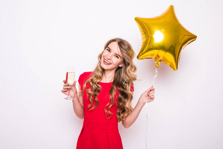 年轻女人穿着红色与金色的星星形气球微笑和在白色背景喝香槟