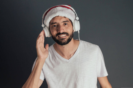 戴着圣诞老人帽和 t恤衫的年轻人在耳机上听音乐