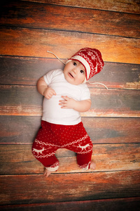 红色的圣诞老人的帽子的小宝贝庆祝圣诞节。戴红色帽子的婴儿的圣诞照片
