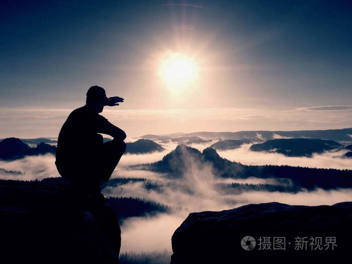 照片 人物 剪影的黑色和帽的独自徒步旅行者坐在悬崖上.