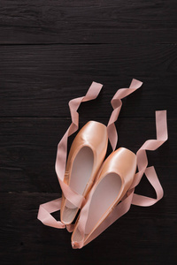 粉色的芭蕾舞足尖鞋黑色木背景