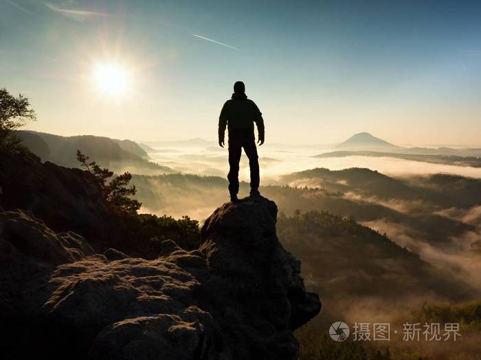高高站在悬崖的人.徒步旅行者爬上岩石峰值和欣赏的景色