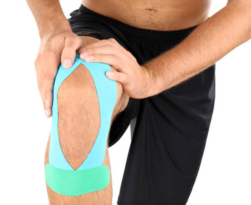 Physio胶带贴在男性膝盖上，与白色隔离