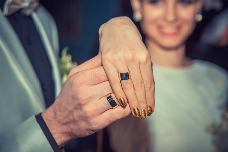 美丽的微笑的新娘，显示带戒指，新郎牵着她的手与结婚戒指的手。标志，象征着新的家庭观念
