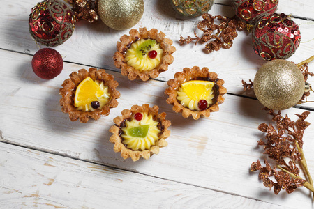 自制甜点与水果为新的一年。假期的甜点。查看从上面。圣诞装饰品和玩具。木制的背景上甜点